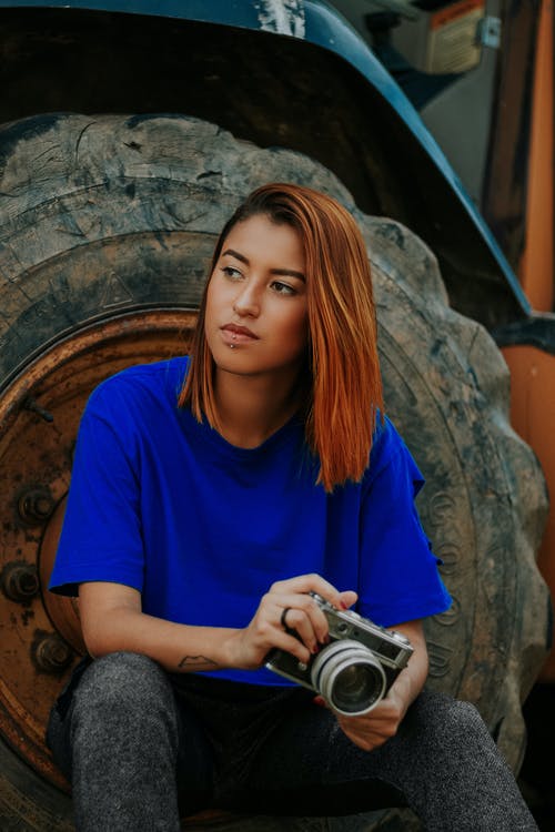 拿着照相机的妇女坐在车胎 · 免费素材图片