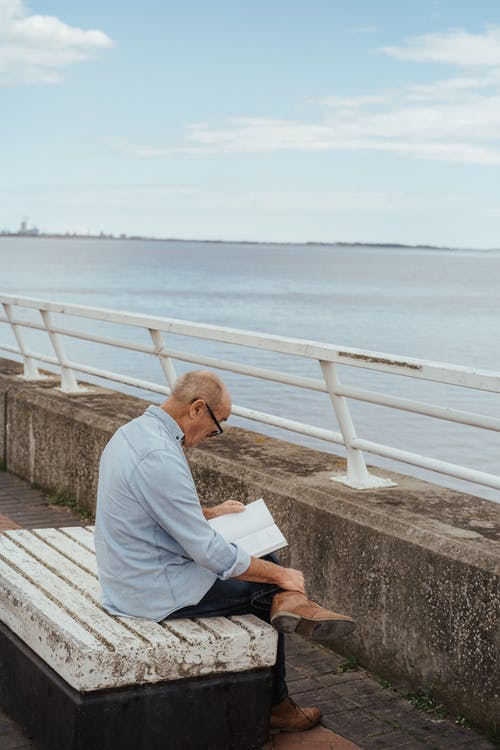 老人看书，坐在路堤上 · 免费素材图片