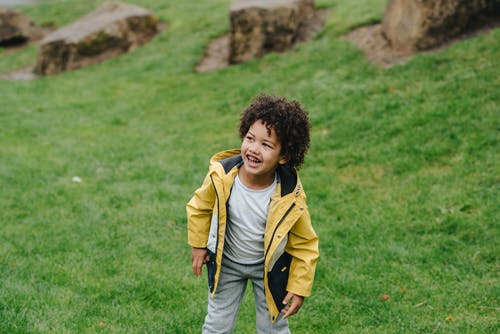 性格开朗的黑人男孩，在绿色的草坪上 · 免费素材图片