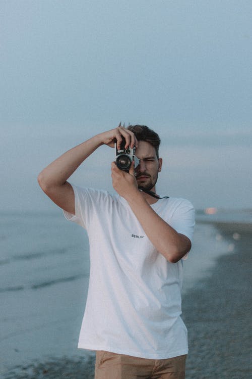 胡子的男子，与站在海边的相机拍照 · 免费素材图片