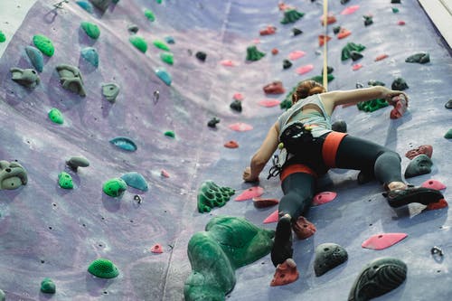 女运动员训练攀岩在健身房的攀岩墙上 · 免费素材图片
