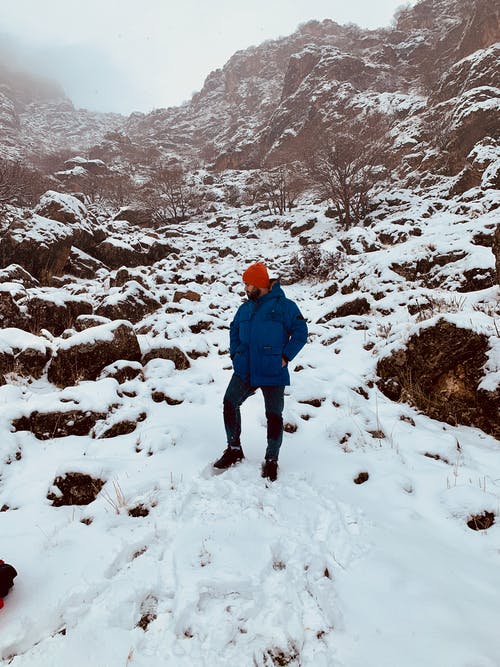 蓝色外套和黑色的裤子，在积雪的地面上行走的人 · 免费素材图片