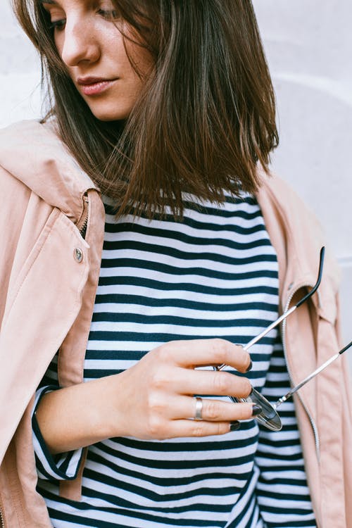 棕色外套拿着黑框眼镜的女人 · 免费素材图片