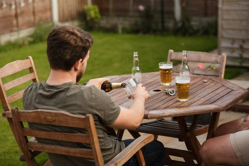 男人与朋友在桌上的杯子里倒啤酒 · 免费素材图片