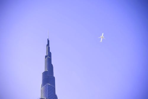 白色飞机飞越大厦 · 免费素材图片