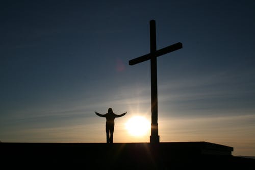 在日落期间站在十字架旁边的人的剪影 · 免费素材图片