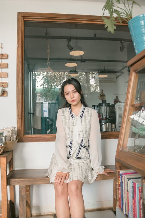 女人穿着白色的长袖连衣裙，坐在木凳上的照片 · 免费素材图片