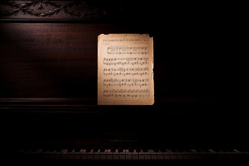靠木制钢琴的音符照片 · 免费素材图片