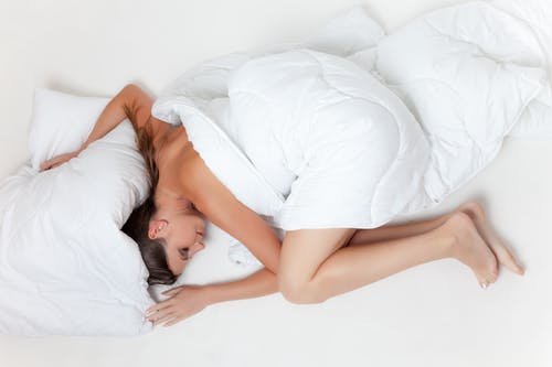躺在白色的纺织触摸白色枕头上的女人 · 免费素材图片