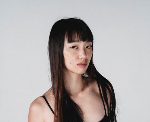 有长的头发的可爱的亚裔妇女对白墙壁 · 免费素材图片