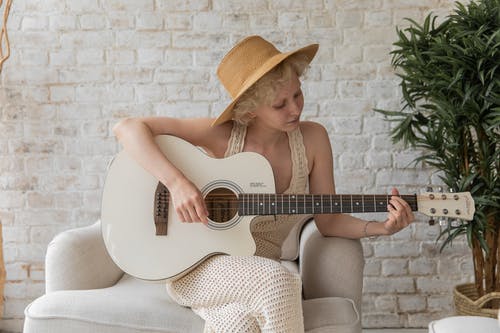 坦然的女人在舒适的公寓里玩吉他 · 免费素材图片
