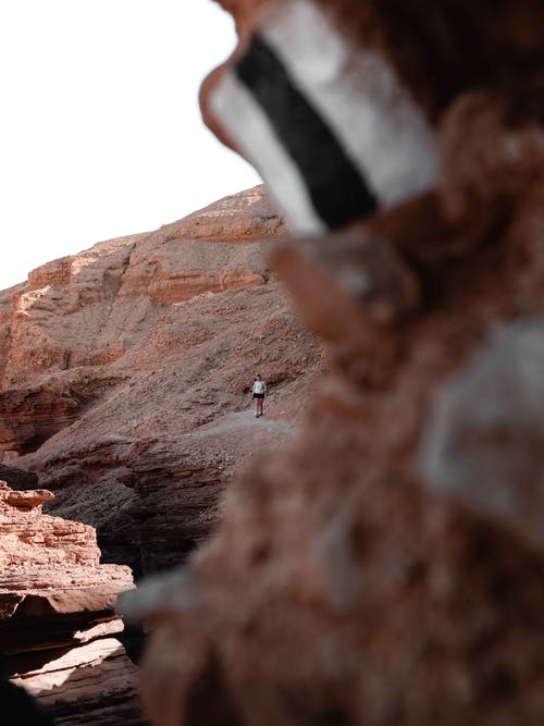 女人站在棕色的岩石 · 免费素材图片