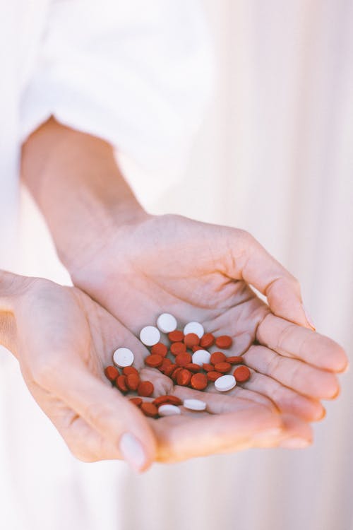 人手上的白色和红色的圆形药物药 · 免费素材图片