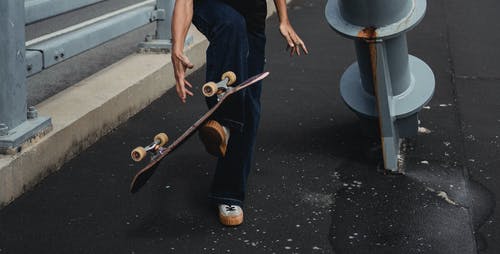 男子抓滑板在沥青街上 · 免费素材图片