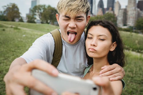 在智能手机上拍照时作物多样的夫妇做鬼脸 · 免费素材图片