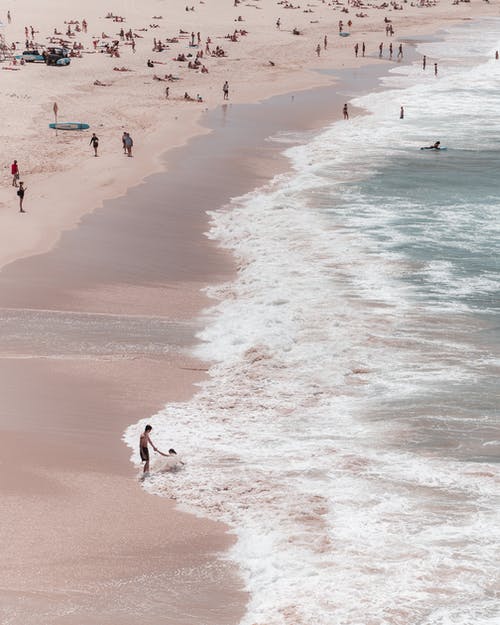 拥挤的海滩被泡沫海浪冲刷 · 免费素材图片