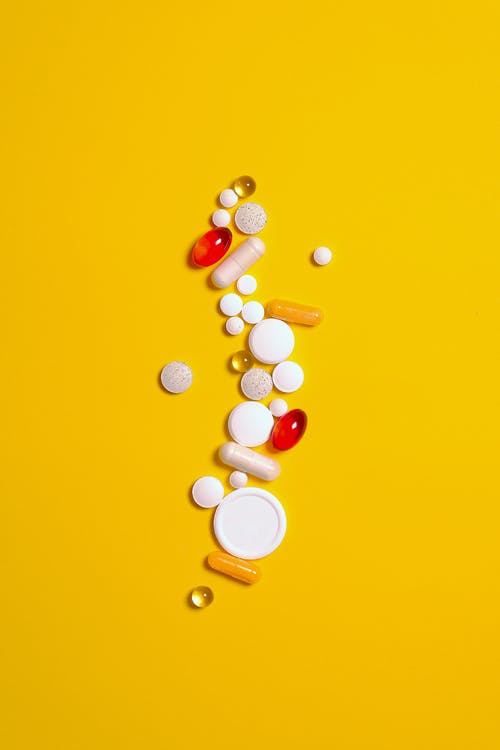 药物治疗药片和胶囊在黄色背景上孤立 · 免费素材图片