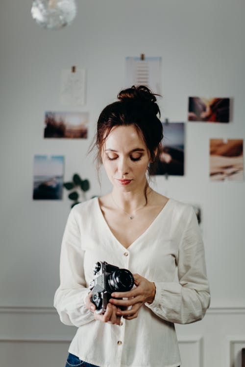 女人穿着白色的衬衫，拿着黑色的相机 · 免费素材图片