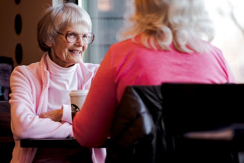 与另一个女人聊天时坐着的老女人的照片 · 免费素材图片