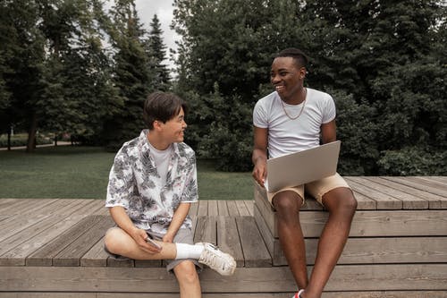 浏览膝上型计算机的快乐的年轻多种族男性朋友在公园 · 免费素材图片