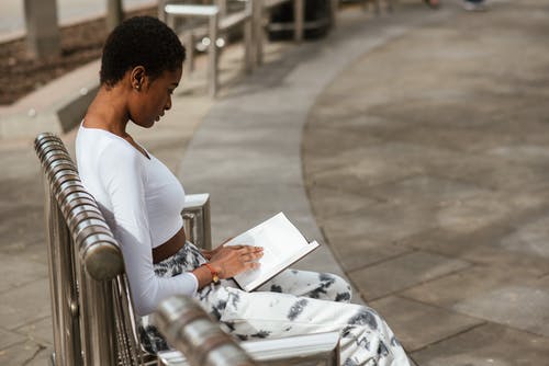在街头长椅上聚焦黑人女性阅读书 · 免费素材图片