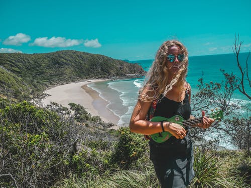 在海边弹吉他时站在山上的女人 · 免费素材图片