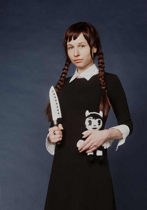 女人拿着刀和娃娃的时候穿着黑色的连衣裙 · 免费素材图片