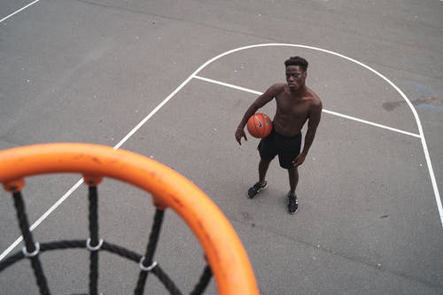 男子站在篮球筐附近举行篮球 · 免费素材图片