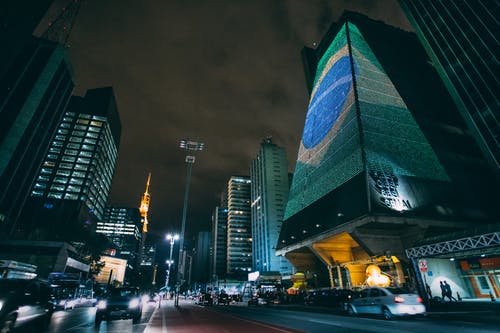 夜间在建筑物之间的道路上行驶的汽车 · 免费素材图片