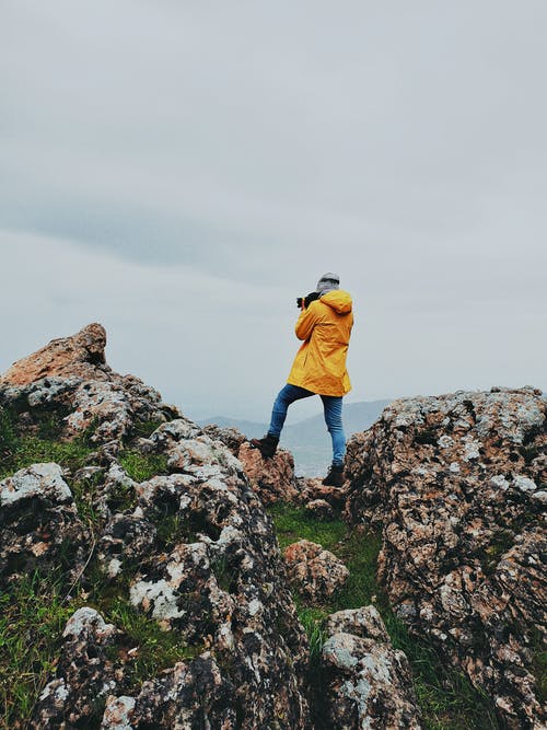 拍照时站在岩石上的人 · 免费素材图片