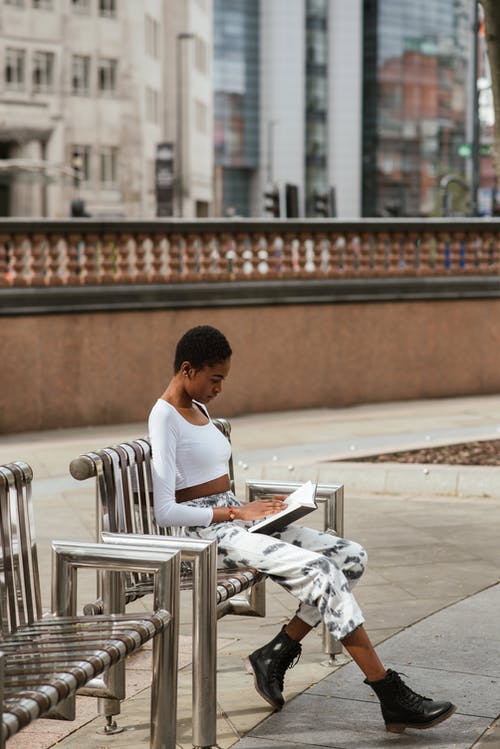 在都市长凳上的黑人妇女读书课本 · 免费素材图片