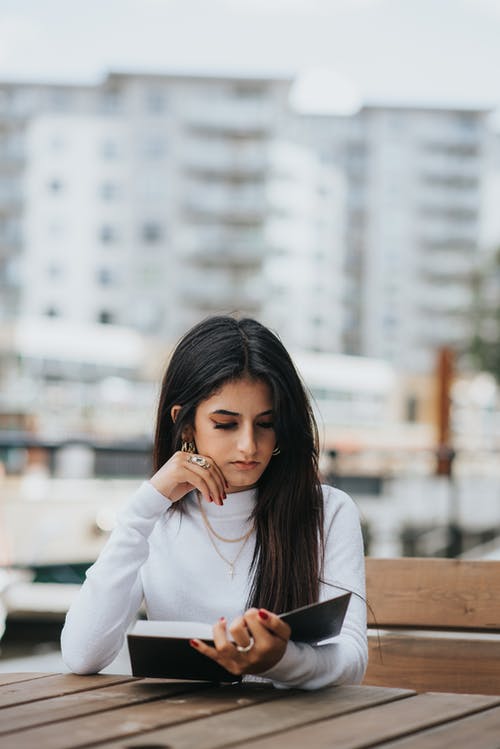 在咖啡馆中沉思的族裔女人看书 · 免费素材图片