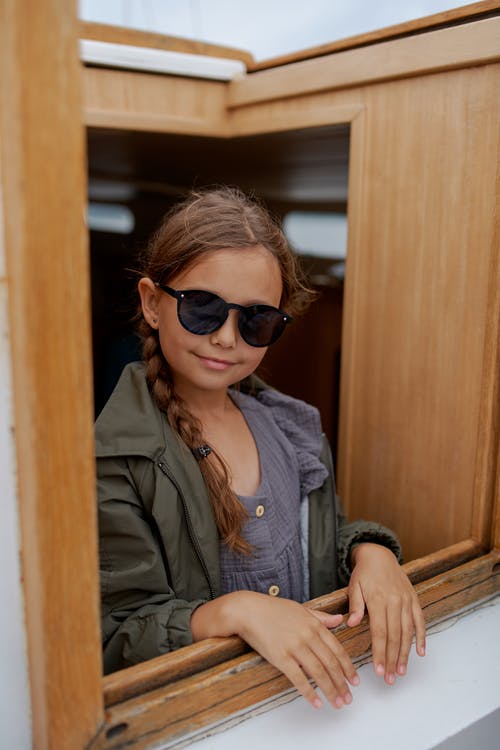 在旅行期间游艇上太阳镜的小女孩微笑着 · 免费素材图片