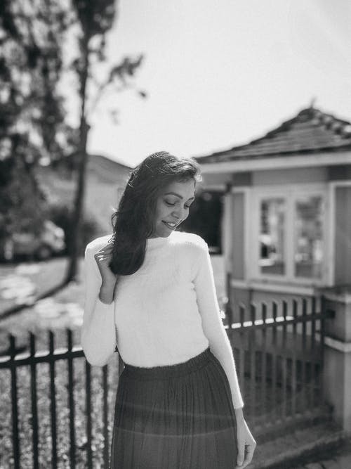 白色长袖衬衫和黑色的裙子站在栅栏附近的女人 · 免费素材图片