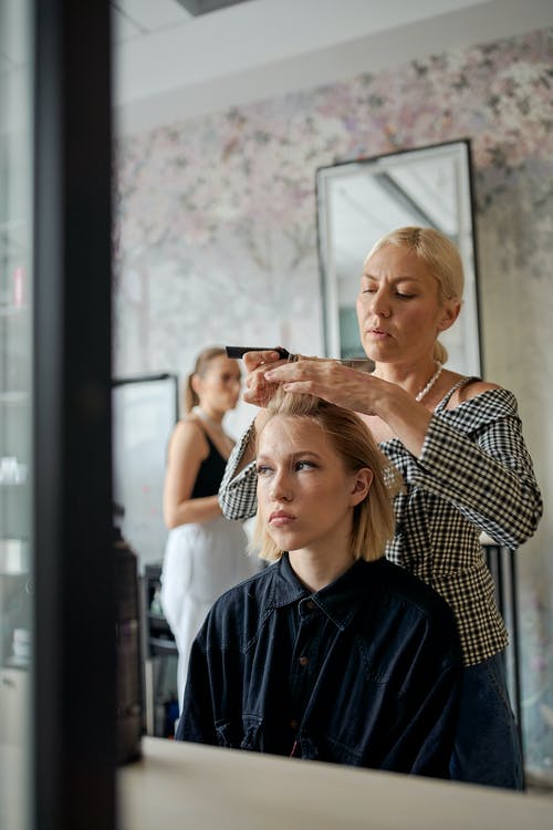集中在沙龙里拉直女人的头发的美发师 · 免费素材图片