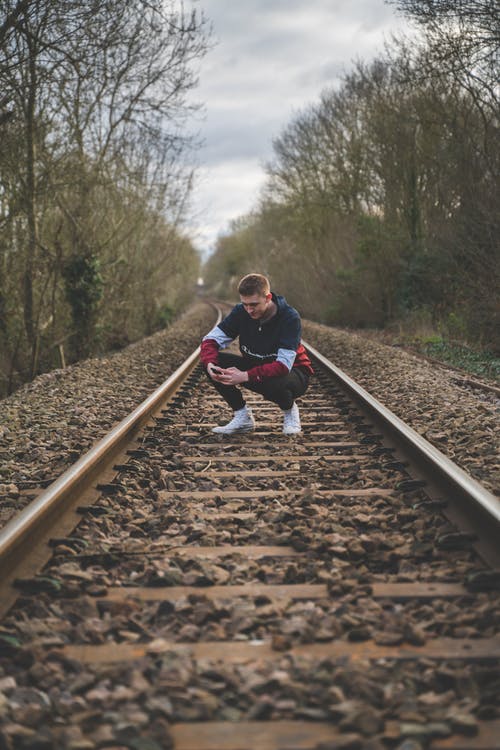 蹲在火车铁轨上的男人 · 免费素材图片