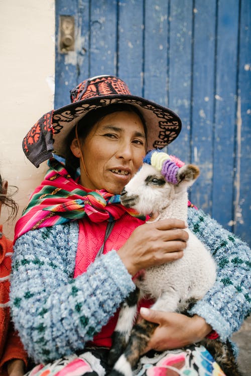 秘鲁女性爱抚婴儿喇嘛在老房子院子里 · 免费素材图片