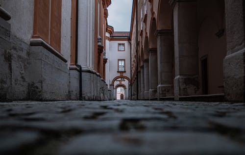 棕色混凝土建筑之间的灰色混凝土走廊 · 免费素材图片