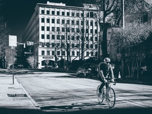 人在公路上骑自行车的灰度照片 · 免费素材图片