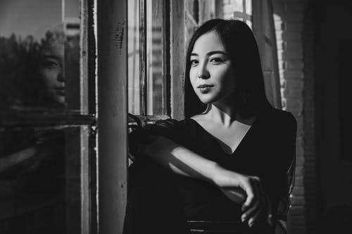 在窗口旁边穿黑色上衣的女人 · 免费素材图片