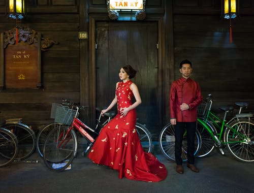 男人和女人在自行车旁边的红色服装 · 免费素材图片