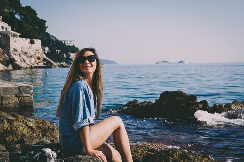 女人坐在海岸线上的岩层 · 免费素材图片