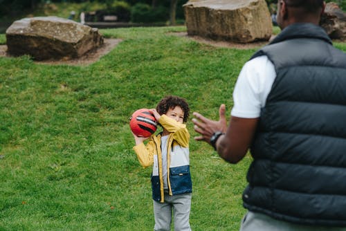 黑人男孩向父亲扔球 · 免费素材图片