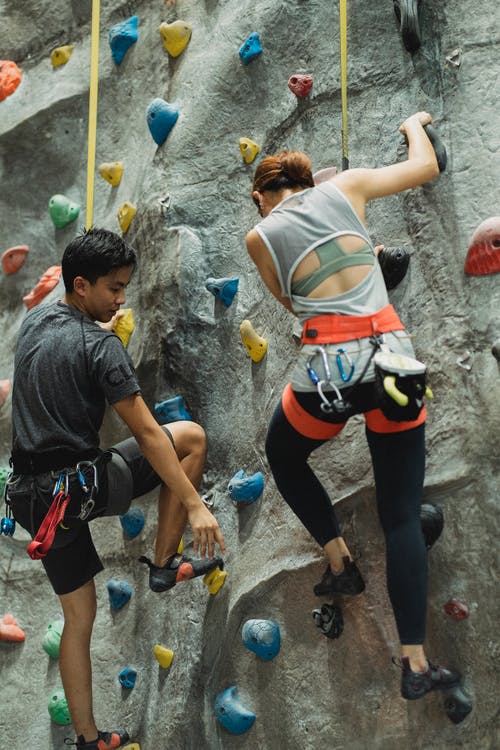 匿名的族裔登山者在训练期间登高人工岩石 · 免费素材图片