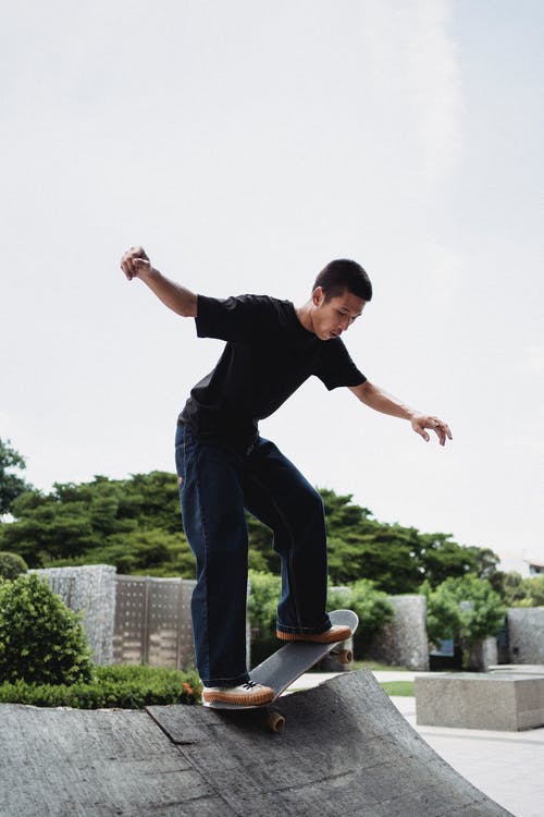 亚洲滑板手在城市坡道上的滑板上保持平衡 · 免费素材图片