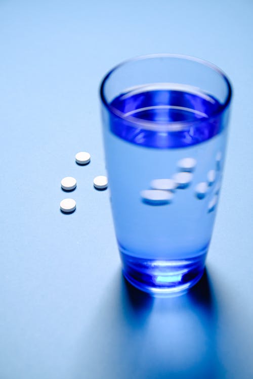 蓝色水和白色药丸的水杯 · 免费素材图片