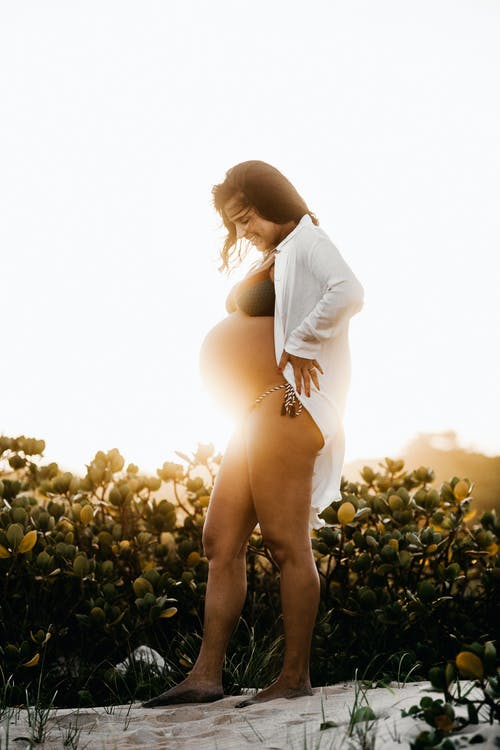 怀孕的女人站在植物旁边 · 免费素材图片