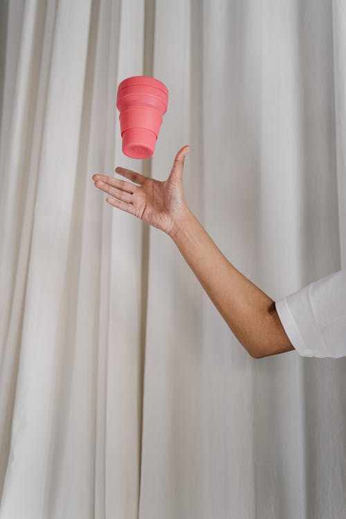人捉粉红色塑料杯 · 免费素材图片