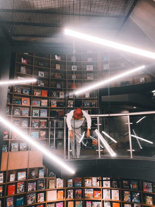 戴着红色帽子的男人倚在栏杆上 · 免费素材图片