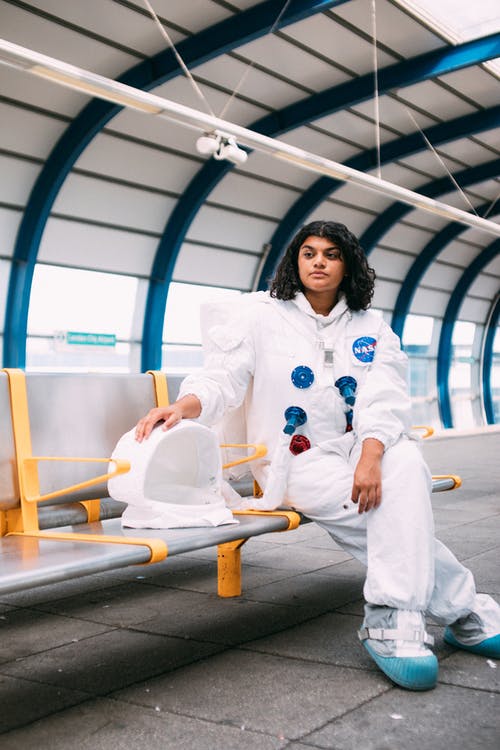 穿宇航员服装，坐在长椅上的女人 · 免费素材图片
